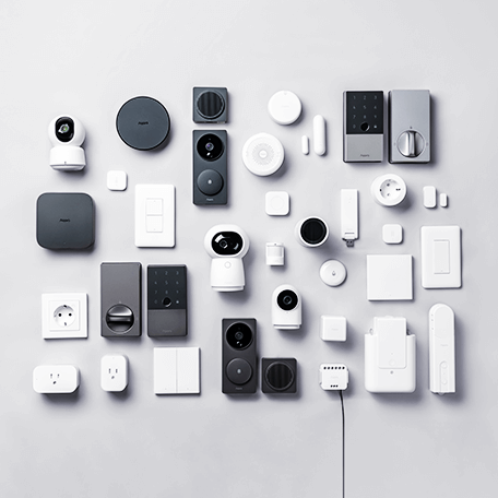 Zestaw urządzeń Aqara smart home na jasnym tle: kamery, czujniki, przełączniki i gniazdka